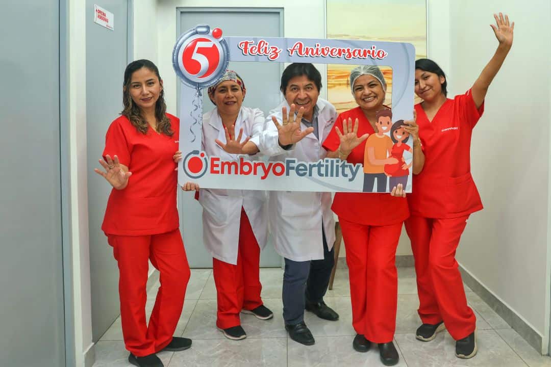 Equipo médico de la clínica de fertilidad EmbryoFertility en Lima celebrando su quinto aniversario, sonriendo y sosteniendo un marco decorativo con el texto "Feliz Aniversario".